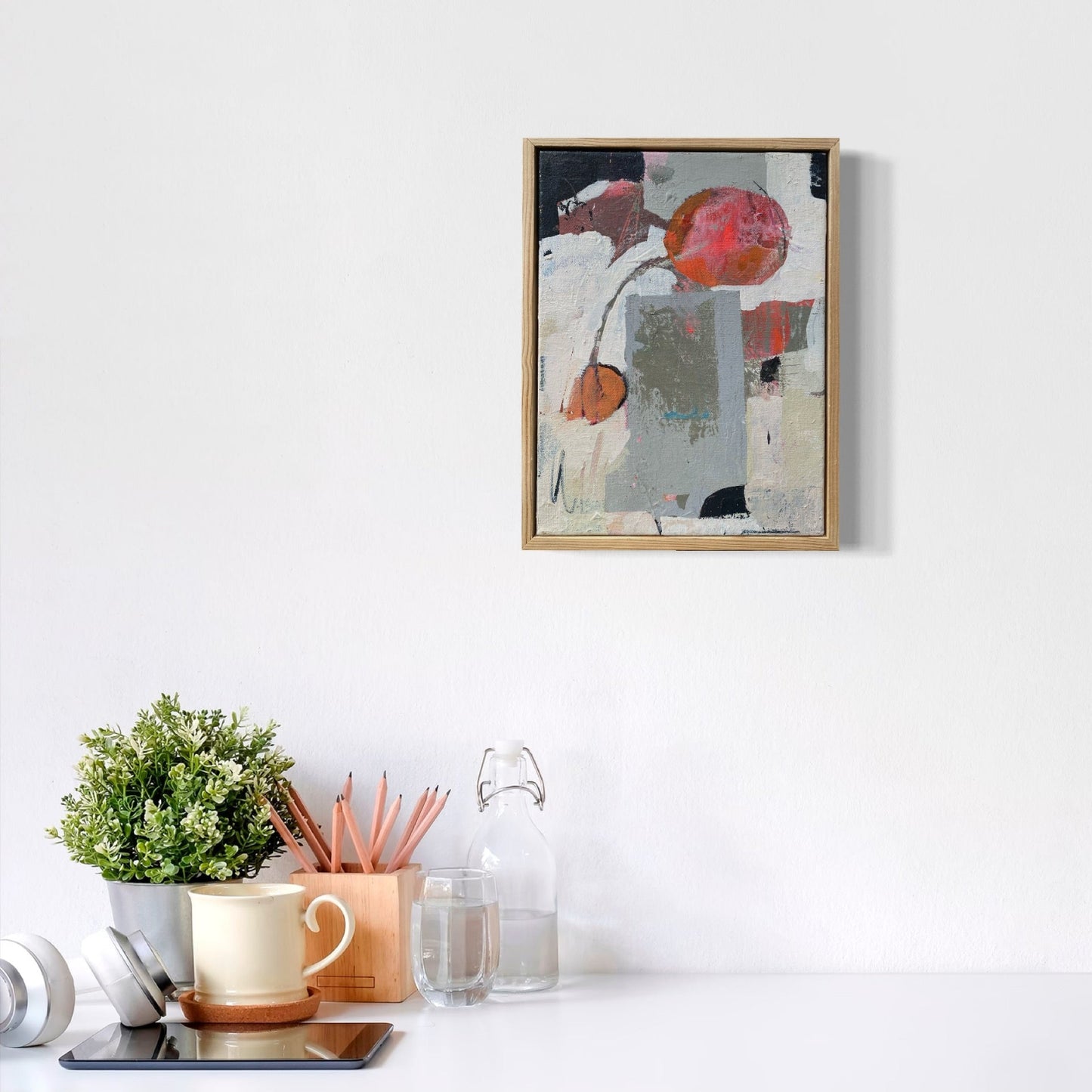 Framed artwork on a white wall with decorative items below