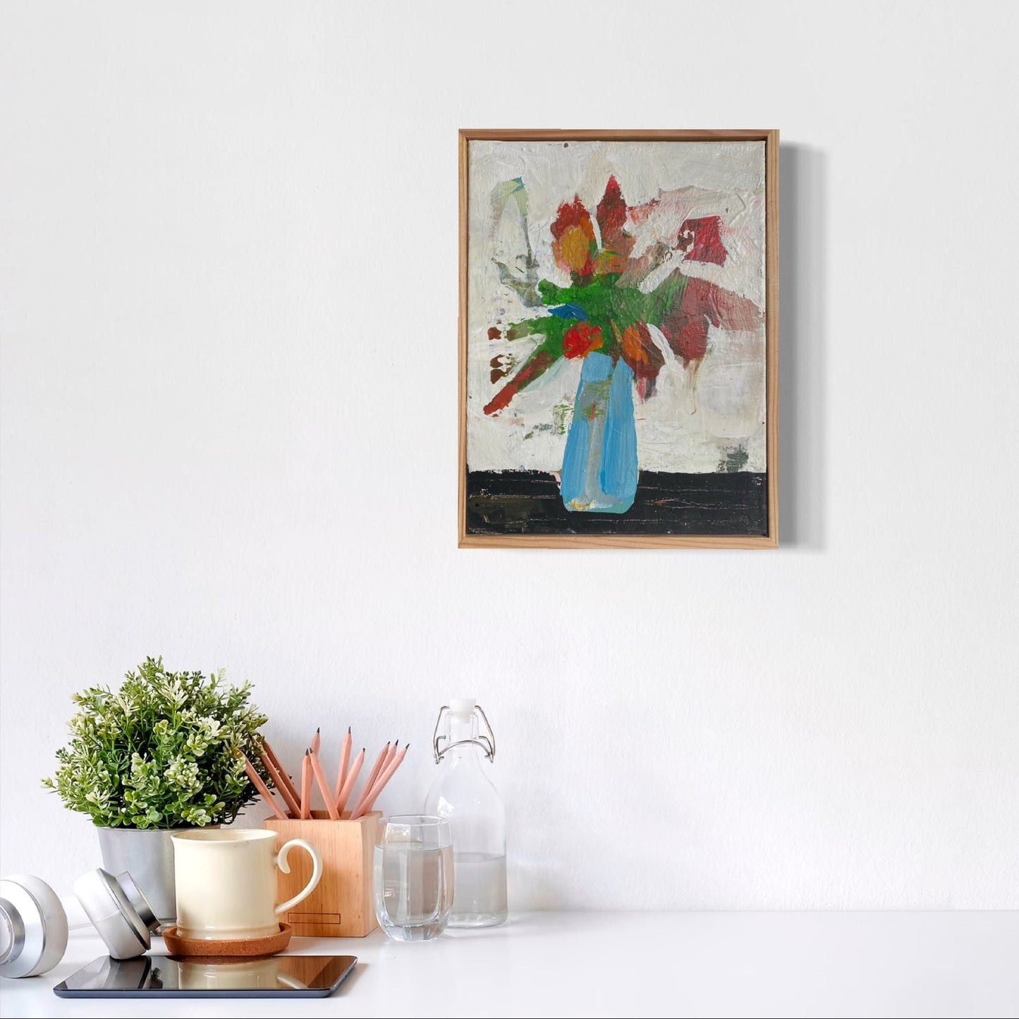 Framed abstract painting on a white wall with decorative items below.