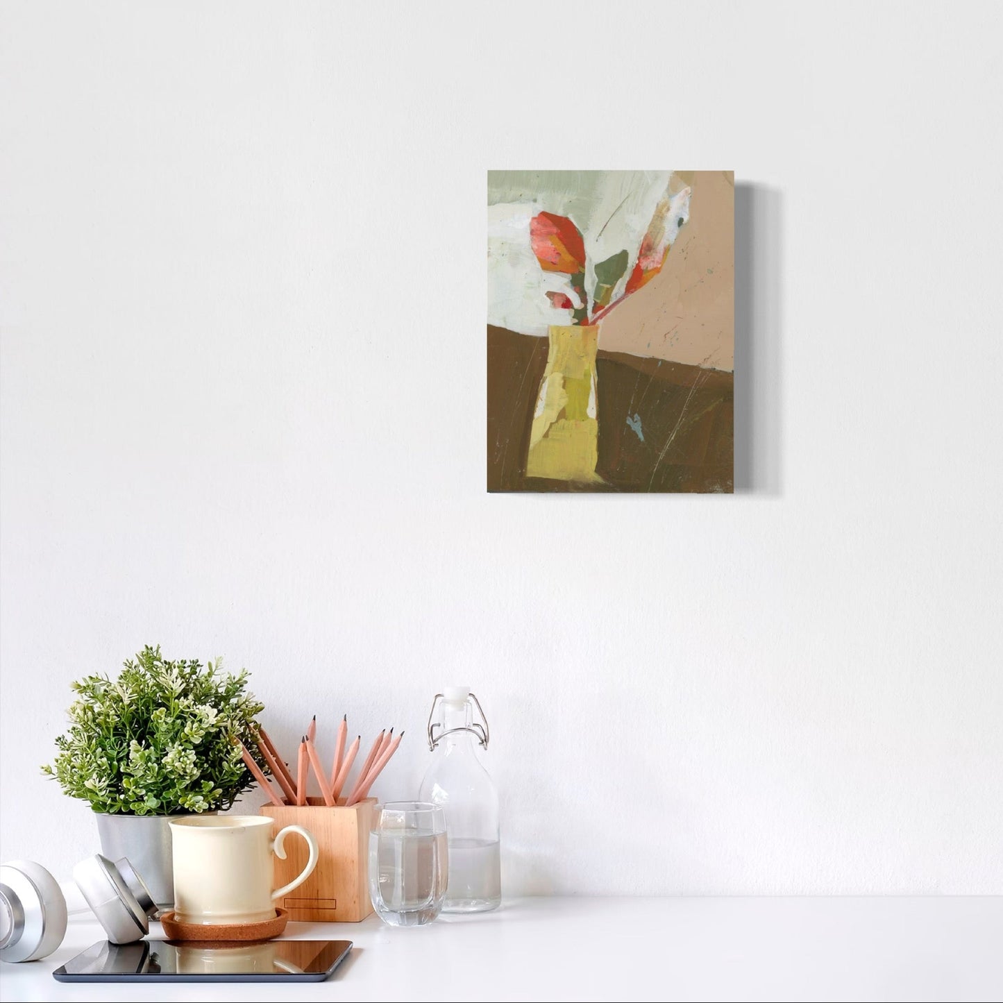 Canvas print of a floral arrangement on a white wall above a desk with office supplies.