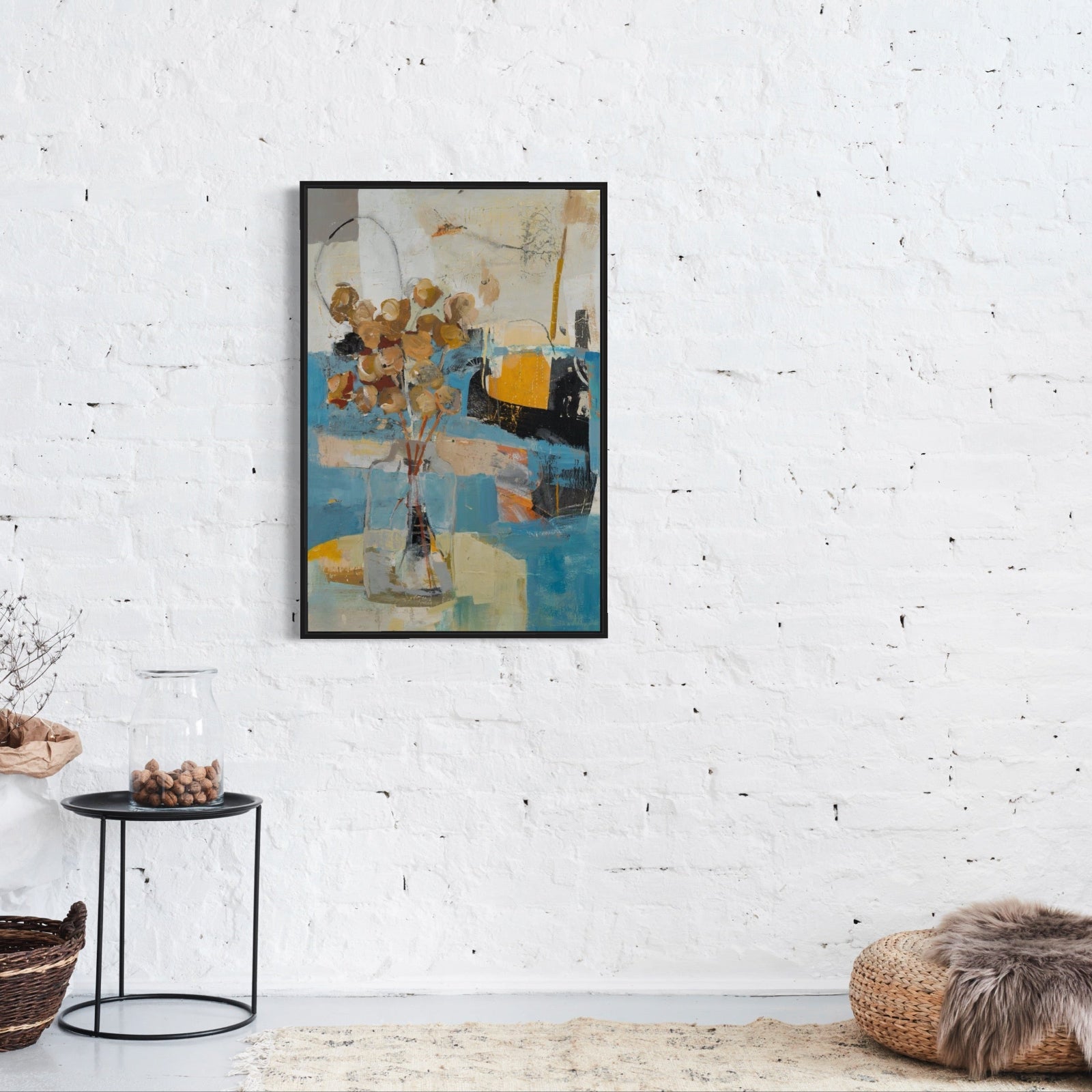 Framed abstract floral painting on a white brick wall with decorative items below.