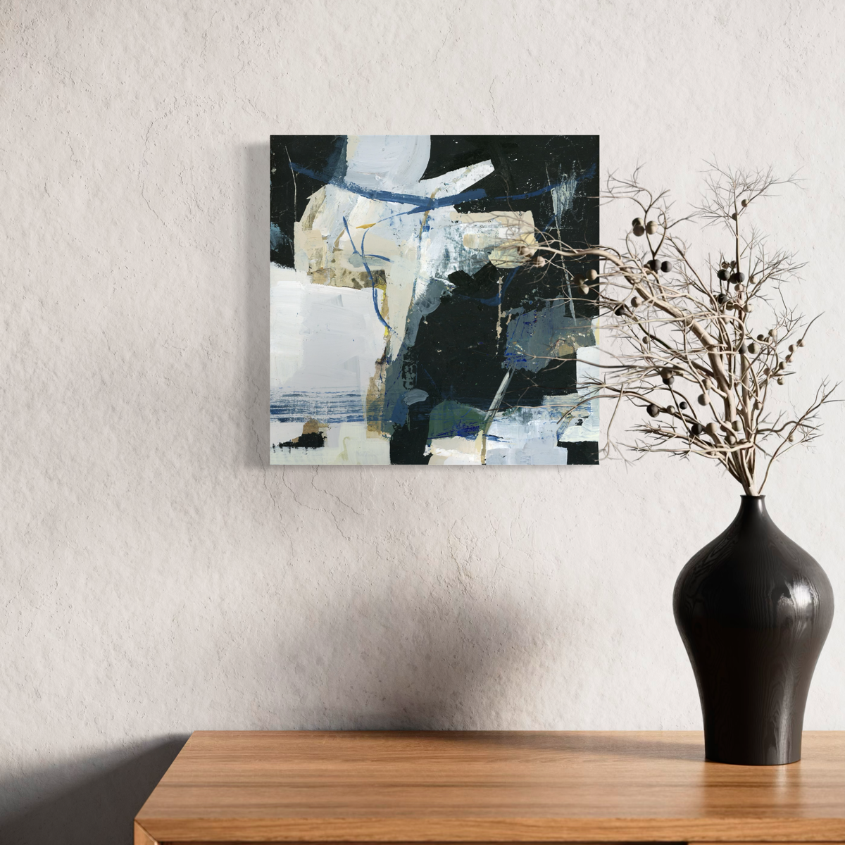 Abstract painting on a wall above a wooden console table with a black vase containing dried branches.